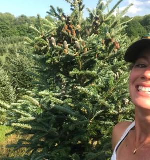 a woman standing in front of a christmas tree