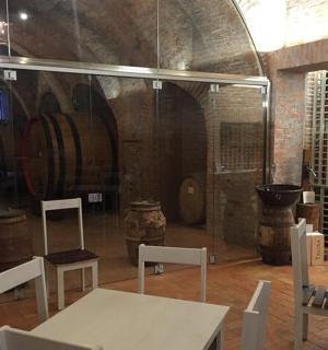 una stanza con un tavolo, sedie e botti di vino