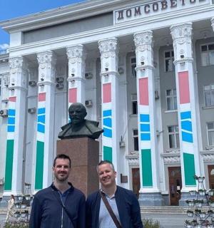 رجلان يقفان أمام مبنى به تمثال