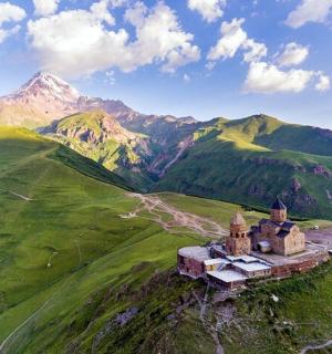 an old castle on a hill with mountains in the background