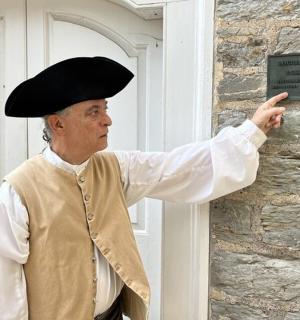 a man wearing a hat pointing at a sign