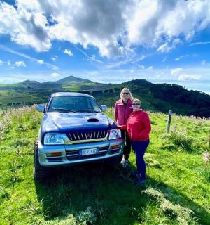 丘の上の車の横に立っている二人の女性