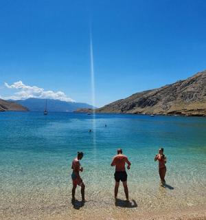 three men standing on a beach in the water
