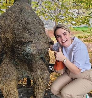 一名女子跪在一尊熊雕像旁