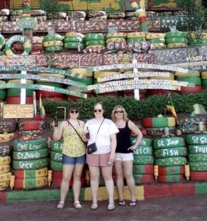three women standing in front of a display of wine bottles