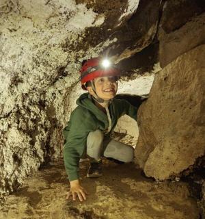 a young boy wearing a helmet in a cave