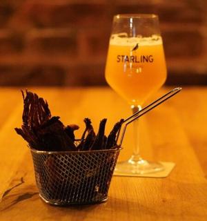 a glass of beer and a basket of pasta on a table