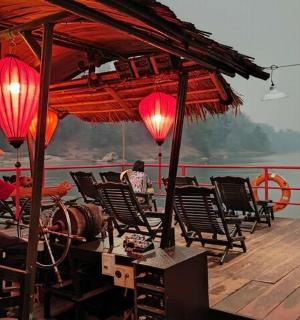 a man sitting on the deck of a boat with red lanterns