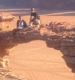 dva lidé sedící na skále v poušti