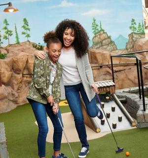 a woman and a young girl playing golf in a park