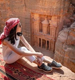 žena sedící na skále vedle starobylé budovy