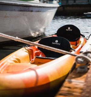 an orange kayak tied to a dock next to a boat