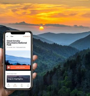osoba držící mobilní telefon před horou