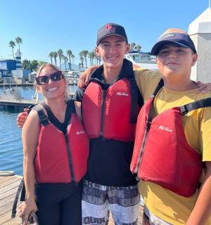 three people wearing life jackets standing on a dock