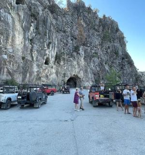 a group of people standing in front of vehicles in front of a mountain