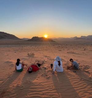 一群人坐在日落时的沙漠中