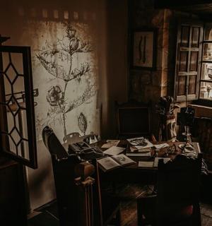 et mørkt rum med et bord og stole og et rum med