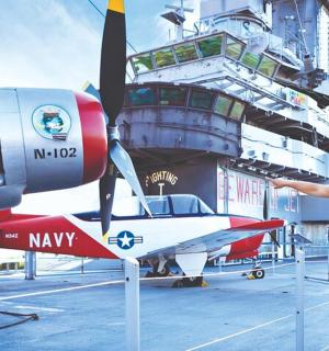a man standing next to a small plane on a ship