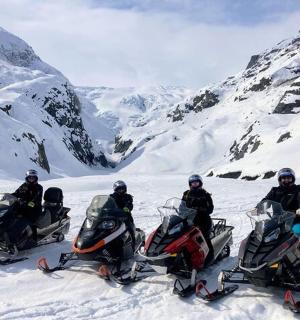 skupina čtyř lidí na sněžných skútrech ve sněhu