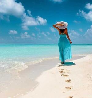 一位身穿蓝色连衣裙的女子在海滩上散步