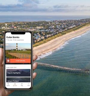 osoba držící mobilní telefon před pláží