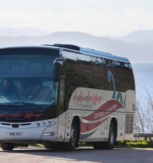 a bus driving down a road next to the water