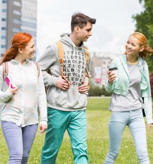 skupina tří lidí procházejících se v parku