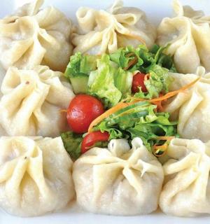 a white plate of dumplings with lettuce and tomatoes