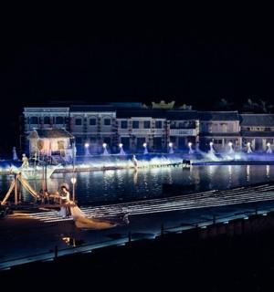 a large building with lights on the water at night