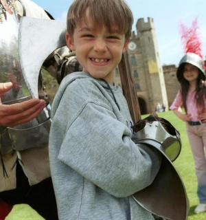 一个小男孩站在骑士雕像旁边