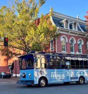 一辆蓝色巴士沿着一栋建筑前的街道行驶