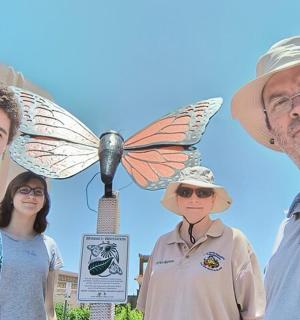skupina lidí stojících před sochou motýla