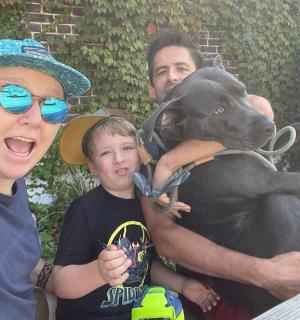 skupina lidí stojící vedle černého psa