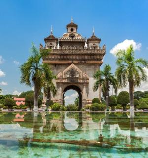 a building with palm trees in front of a pond