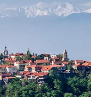 a town on a hill with mountains in the background