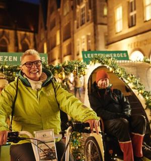 一群人骑着自行车沿着挂满圣诞灯的街道行驶