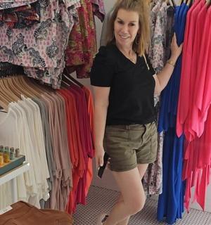 a woman is standing next to a rack of clothes