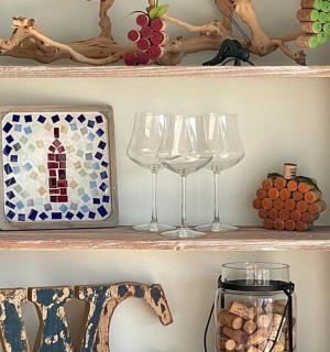 police s sklenicemi na víno a vázou