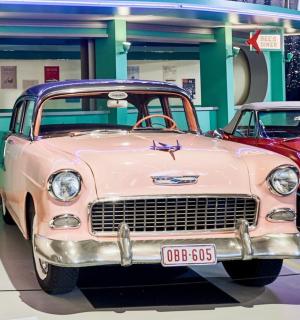 two old cars are parked in a garage