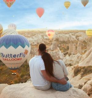 一男一女坐在岩石上观看热气球