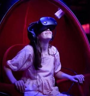 一个戴着头盔坐在红色椅子上的小女孩