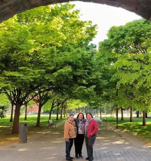 three people standing under an archway in a park