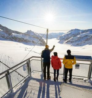 กลุ่มคนสามคนยืนอยู่บนจุดชมวิวท่ามกลางหิมะ