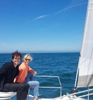 a man and woman sitting on the back of a sailboat