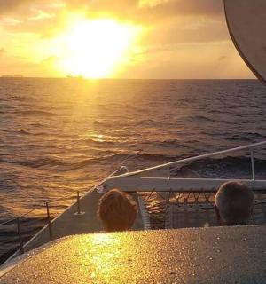 a group of people sitting on a boat watching the sunset