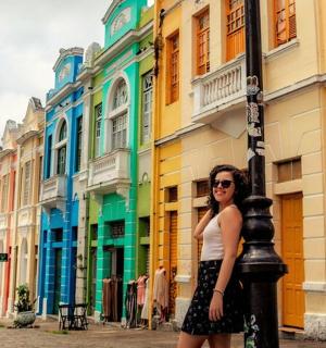 Una mujer parada junto a un poste frente a un edificio.
