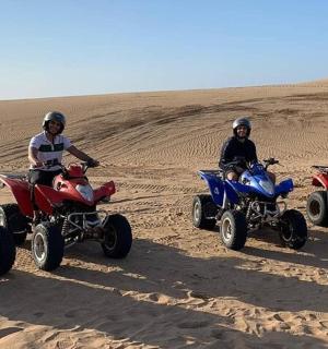 skupina lidí jedoucích na čtyřkolkách v poušti