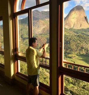 一名男子透过窗户拍摄山峰