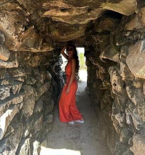 一位身穿红裙的女子站在石墙边