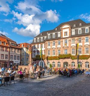 一群人坐在街道两旁的桌子旁，街道上有建筑物